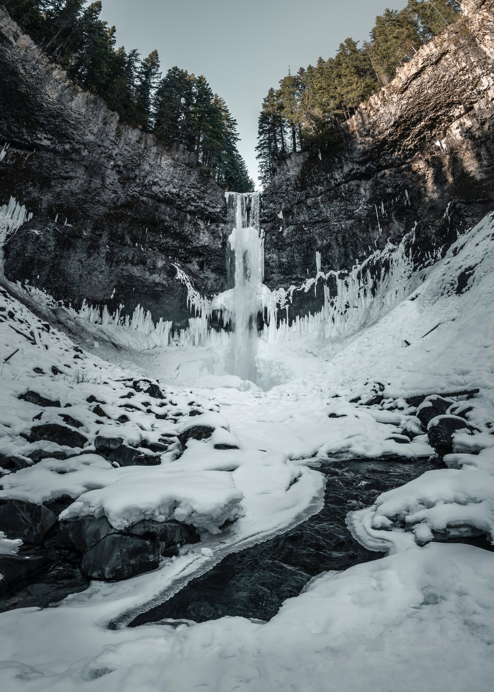 Hay una cascada que está congelada en medio de un bosque nevado (cascada, naturaleza, agua, invierno, nieve)