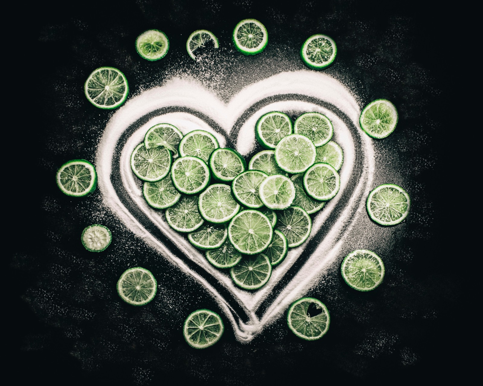 Un primer plano de un corazón hecho de limas y azúcar (cítricos, lima, lime, fruta, verde)