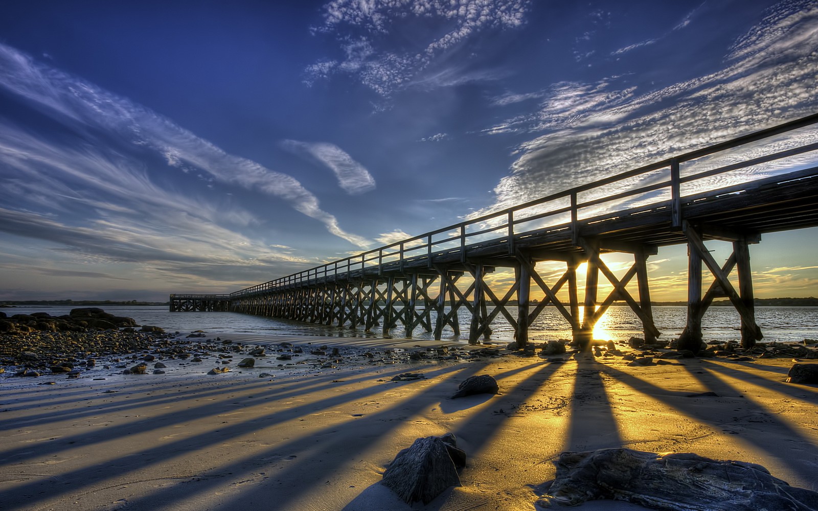 Una vista de un muelle con un largo puente de madera sobre el agua (agua, puente, nube, muelle, horizonte)