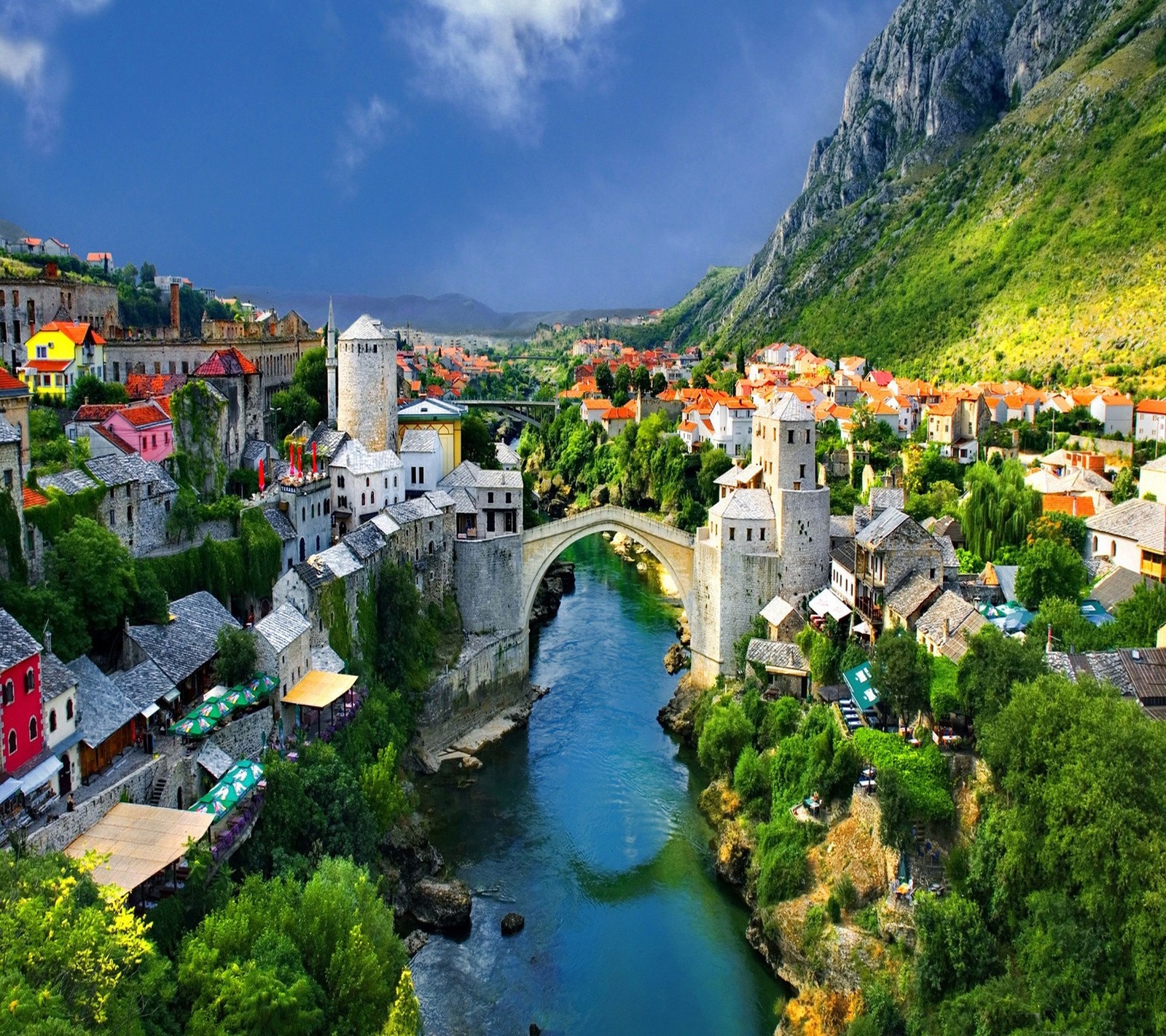 A view of a river running through a lush green valley (city, europe, mountain, river, town)