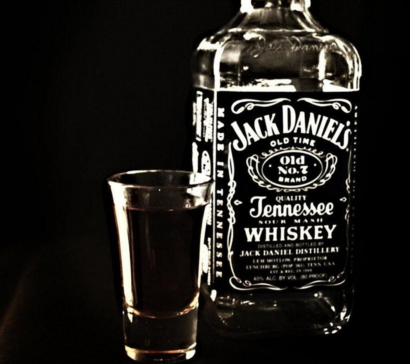 Il y a un verre à shot et une bouteille de whisky jack daniels (alcool, génial, boisson, verre, jack daniels)