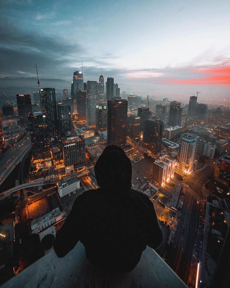 Arafed view of a city at dusk with a person standing on a ledge (city, unknown, person, photographer, hd)