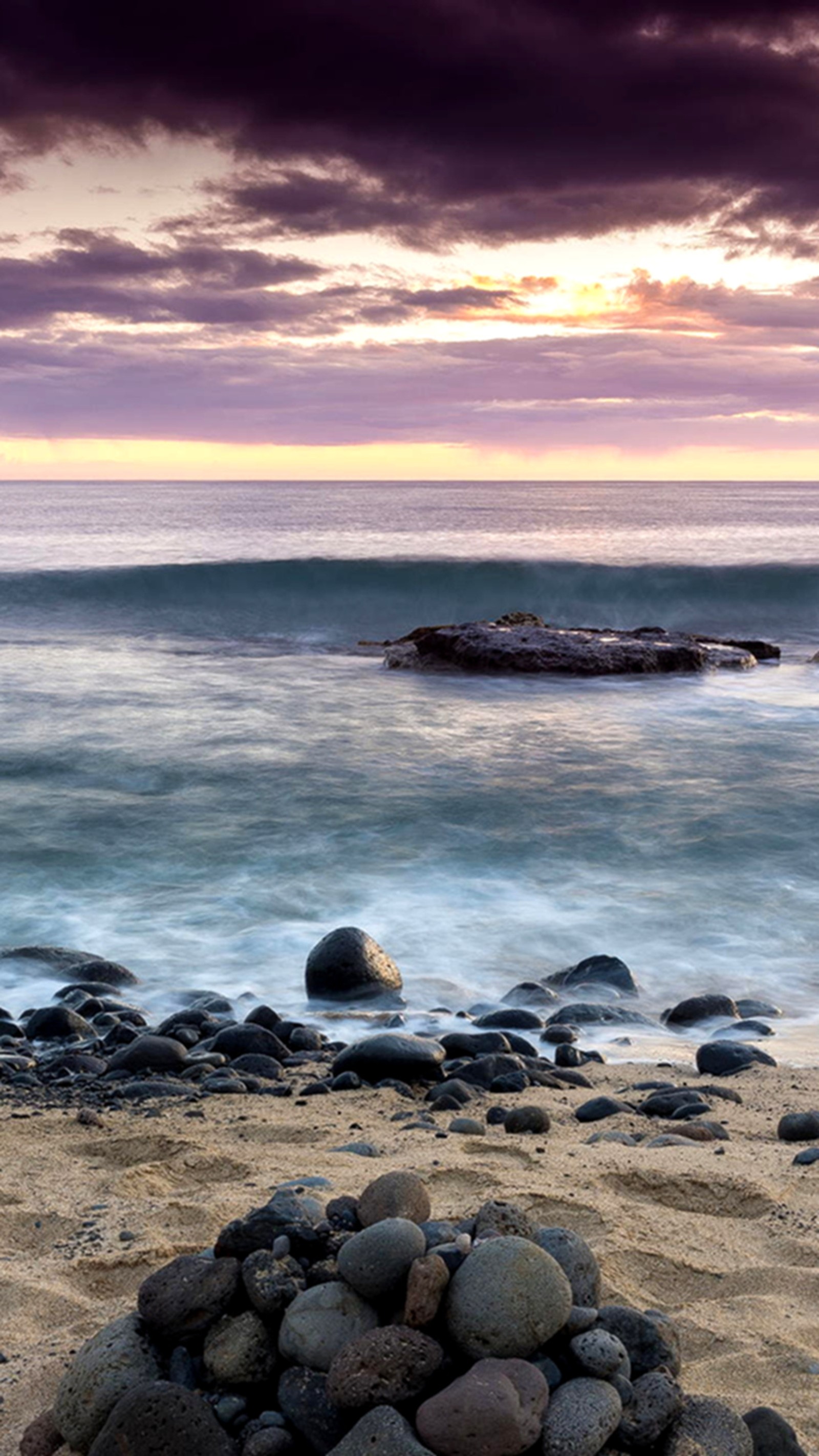 Há um monte de pedras na praia perto do oceano (praia, céu)