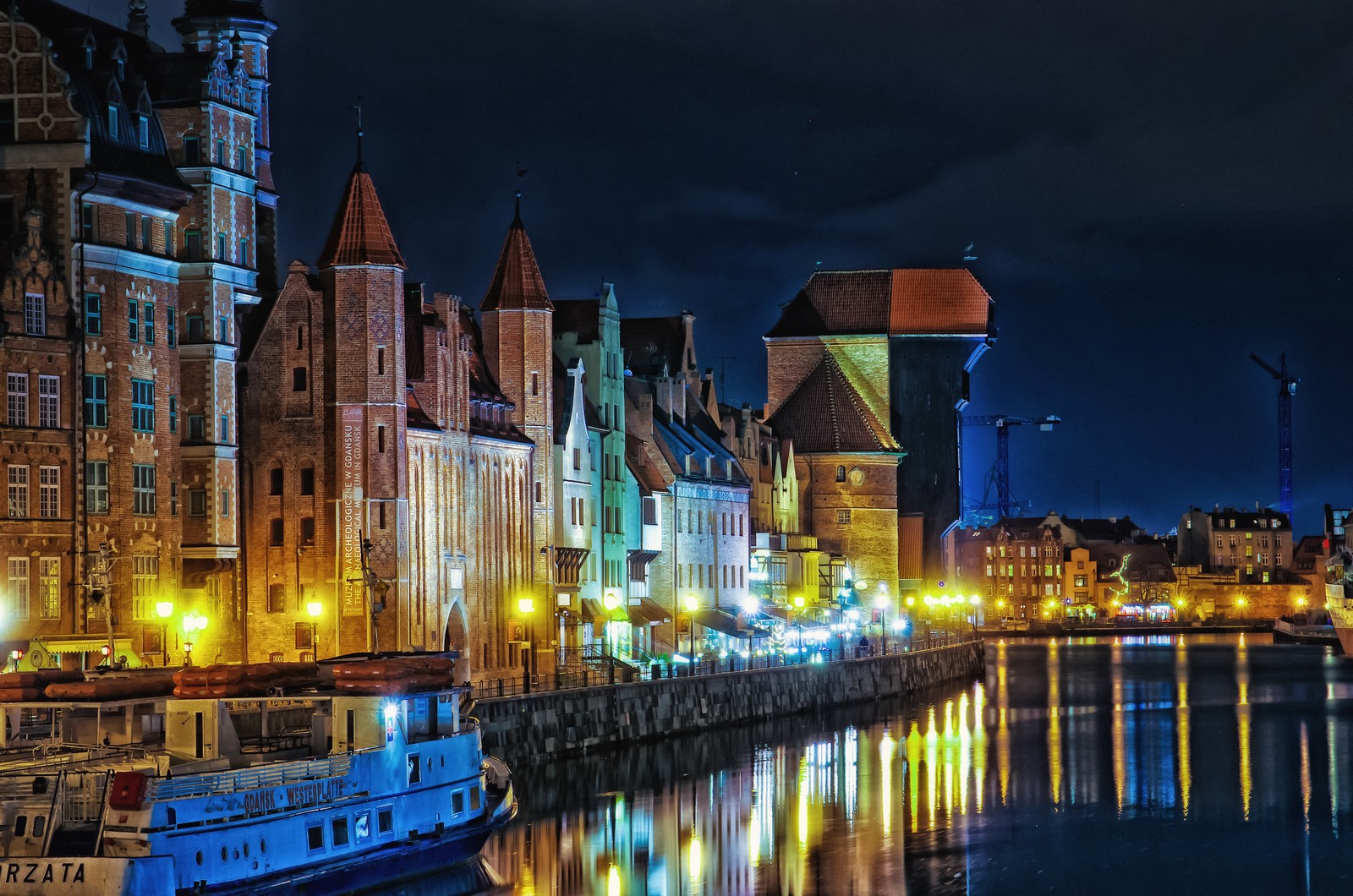 Vista arafada de uma cidade à noite com um barco na água (noite, cidade, paisagem urbana, reflexo, marco)