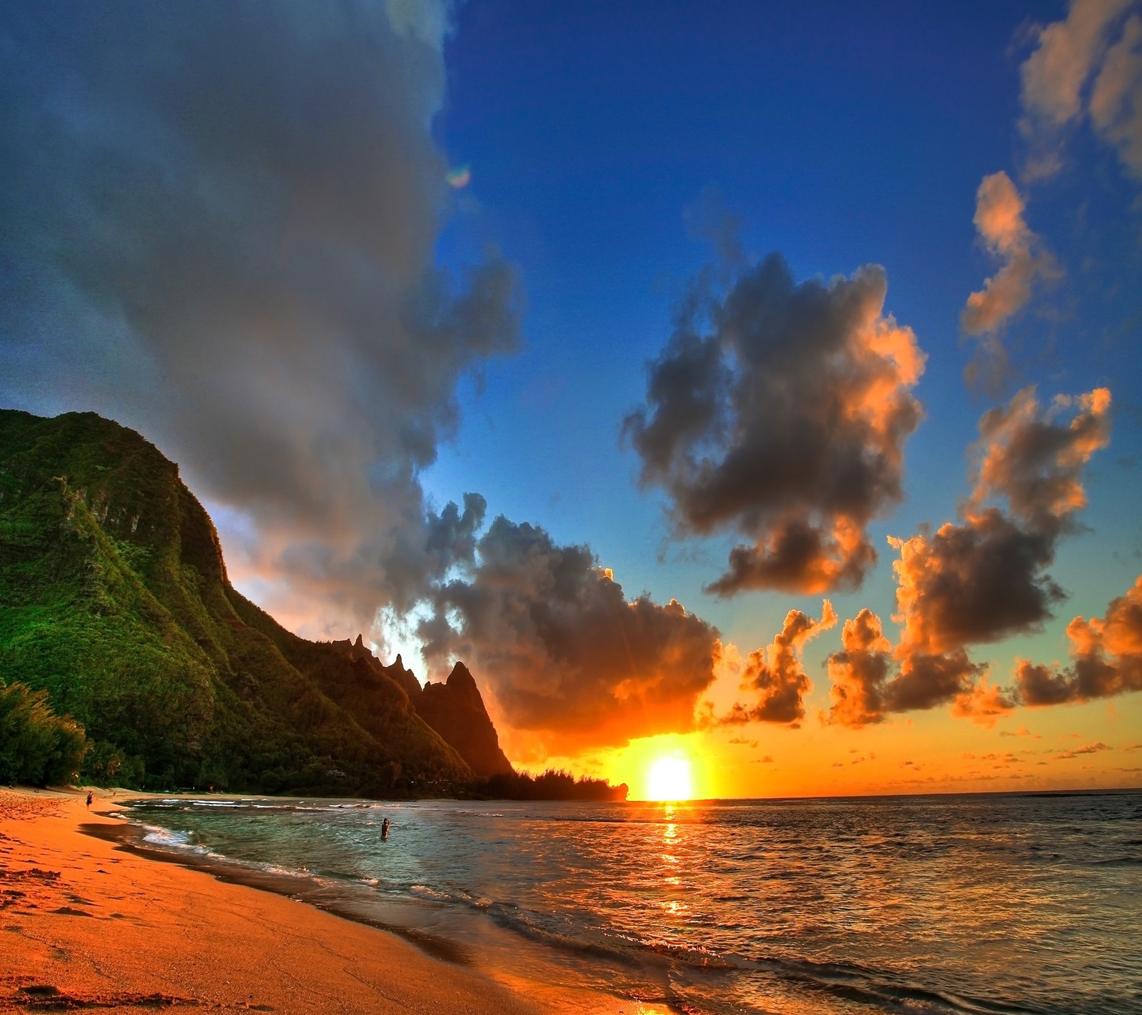 Pôr do sol em uma praia com uma montanha ao fundo (praia, oceano, areia, mar, água)