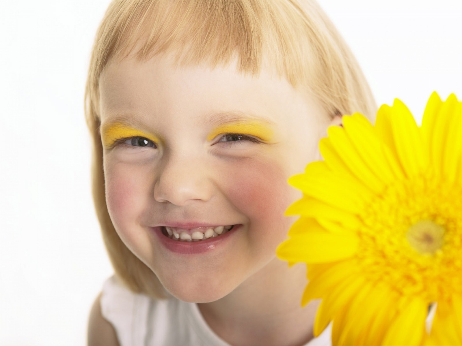 Niña rubia con ojos amarillos y una flor amarilla frente a ella (amarillo, expresión facial, ceja, nariz, mujer)