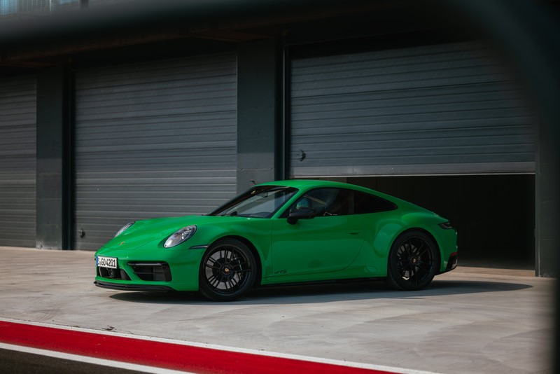 Крупный план зеленого спортивного автомобиля, припаркованного перед гаражом (porsche 911 carrera gts, 2021, спортивные автомобили, 5k, машины)