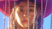 Irene from Red Velvet with glamorous styling, captured behind shimmering beads, exuding a captivating presence.