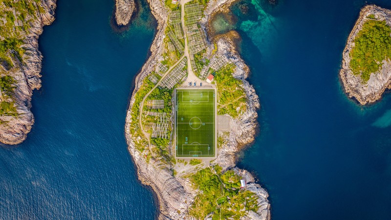 Аэроснимок футбольного поля, окруженного деревьями и водой (henningsvaer stadium, футбольное поле, норвегия, вид с воздуха, мир)