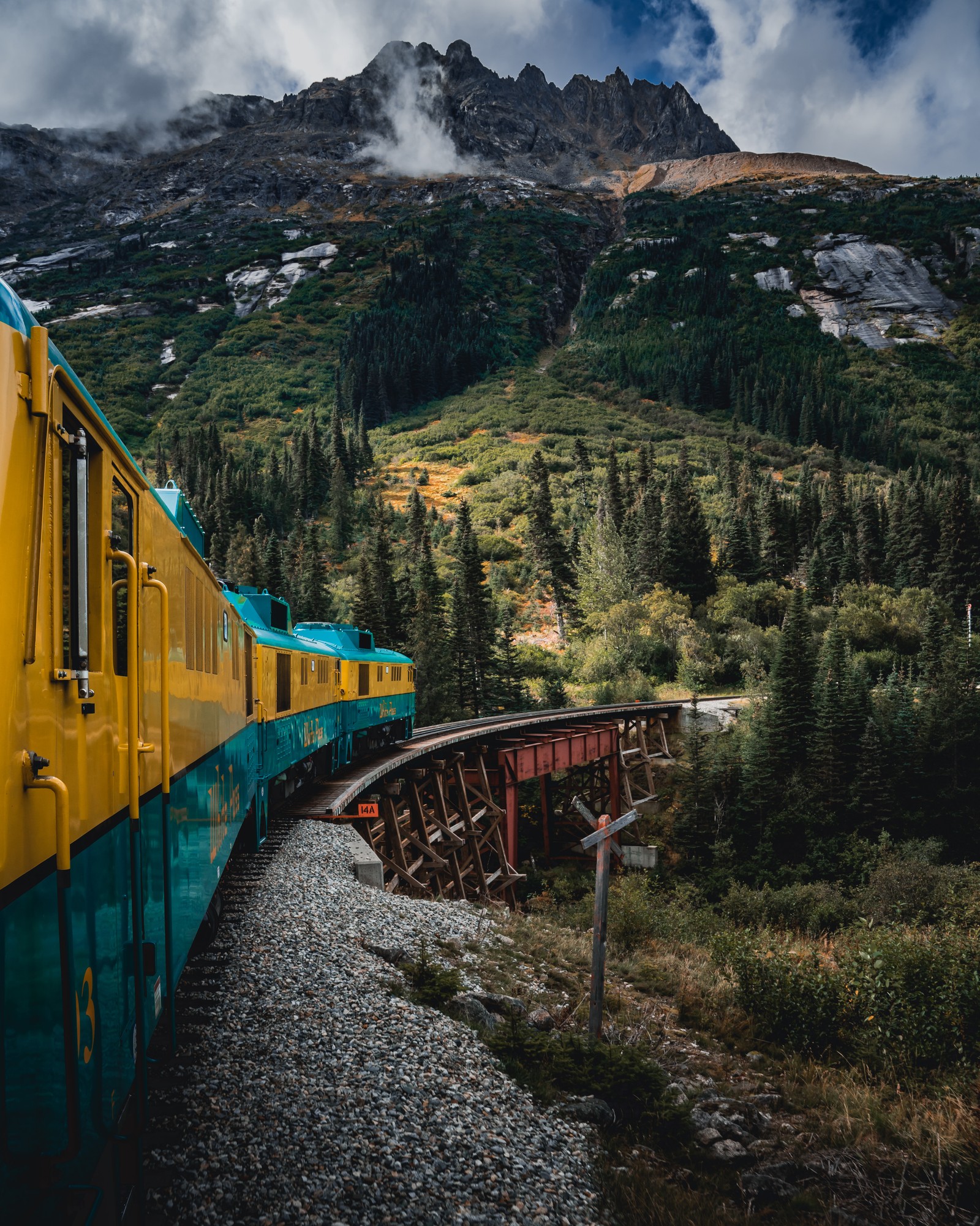 Hay un tren que va por las vías cerca de una montaña (tren, transporte ferroviario, transporte, naturaleza, montaña)