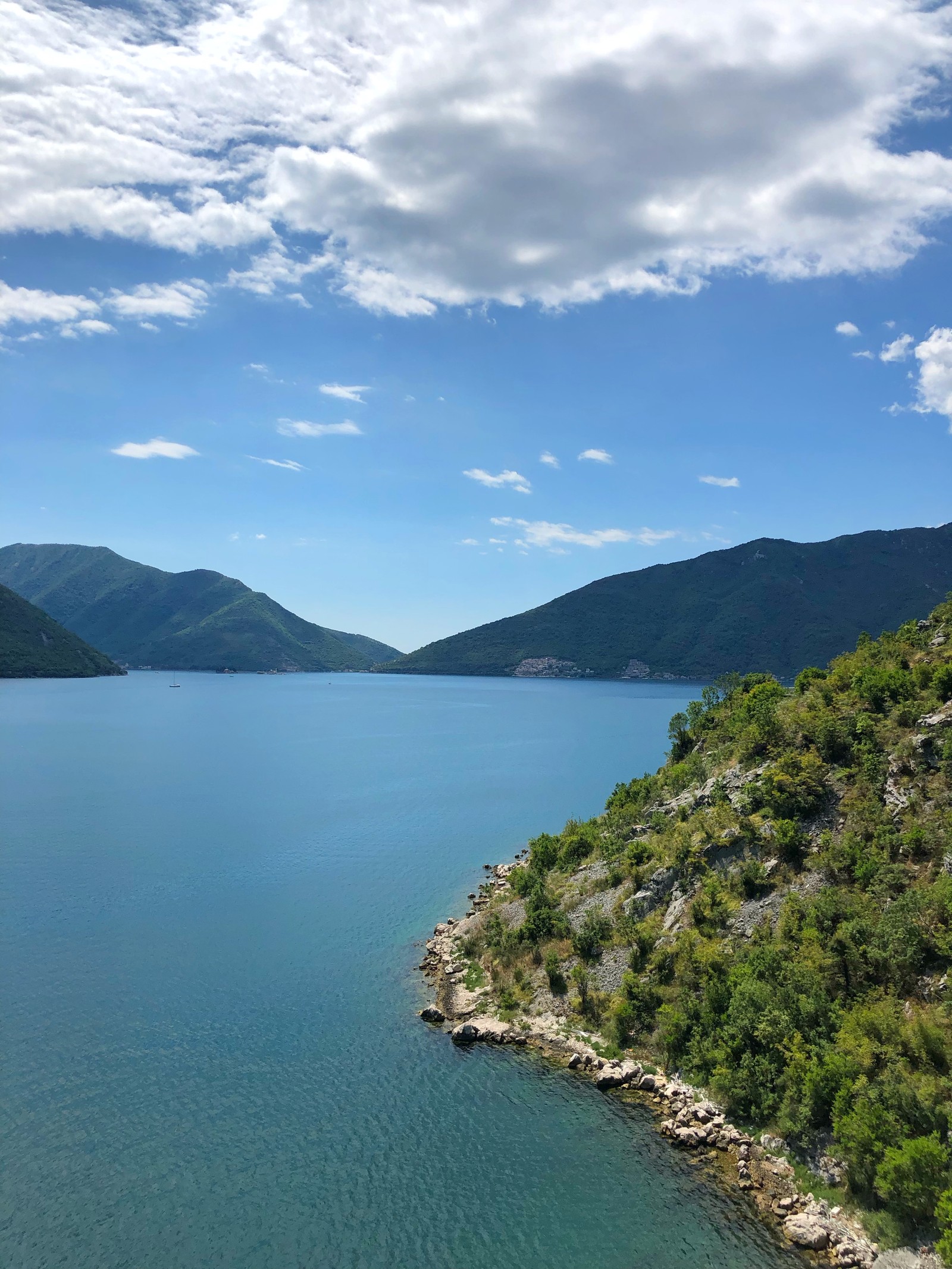 Há um trem nos trilhos perto da água (corpo de água, natureza, azul, formas montanhosas, recursos hídricos)