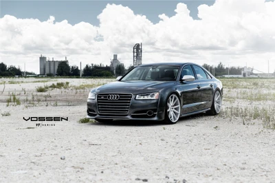 Sleek Audi A8 on custom Vossen wheels in a modern industrial landscape.