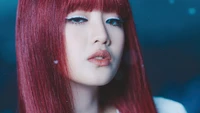 Minnie do (G)I-DLE exibindo um visual marcante com cabelo vermelho vibrante e maquiagem cativante.