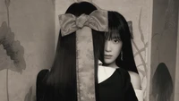 Irene from Red Velvet gazes intently, her image partially obscured by long, dark hair and a traditional bow, creating a striking contrast between modern and classic elements.