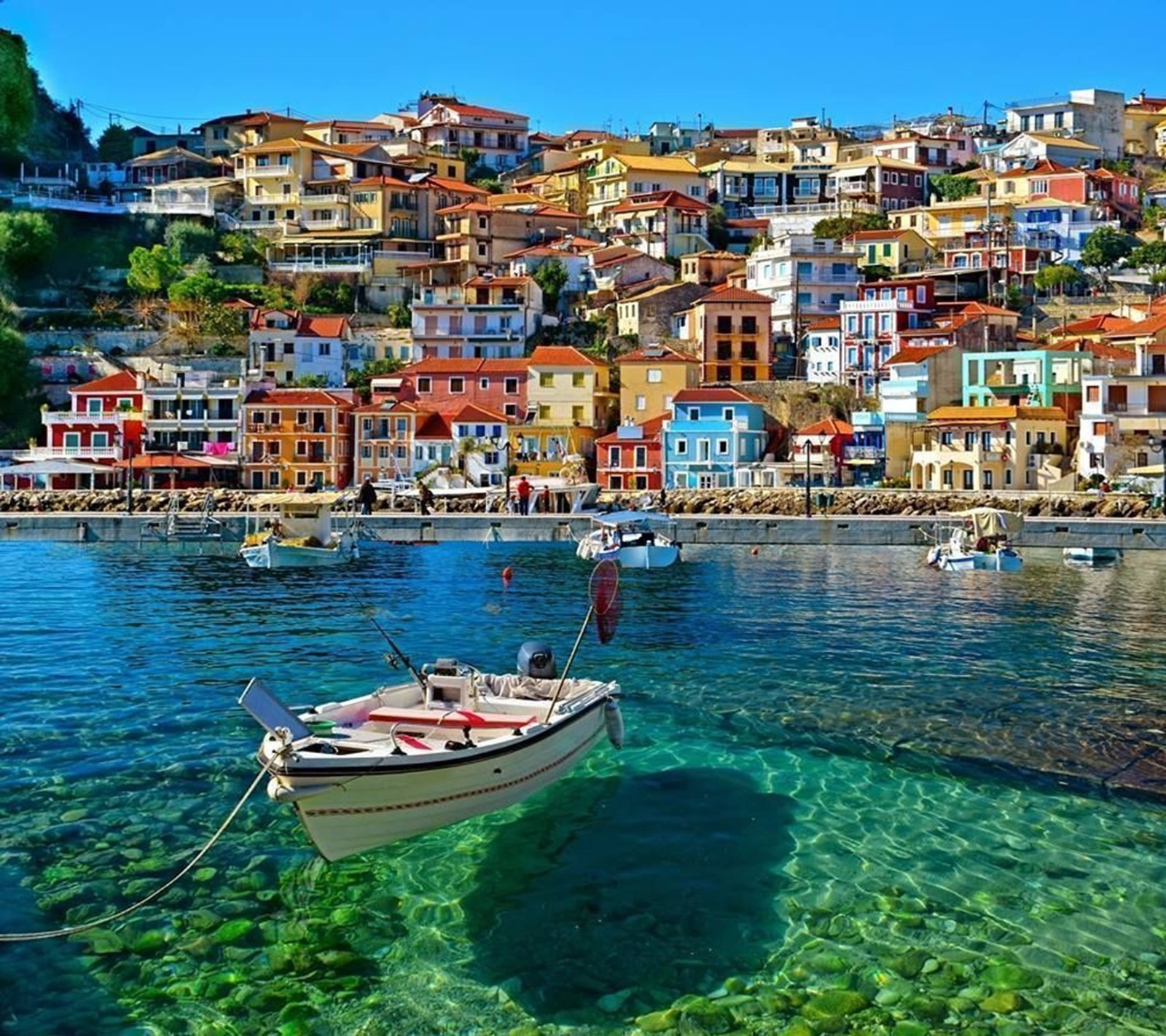 Boats are docked in the clear water near a small town (ree, tsg)