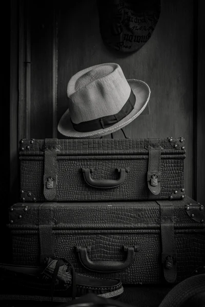 Valises vintage et chapeau fedora dans une élégance monochrome