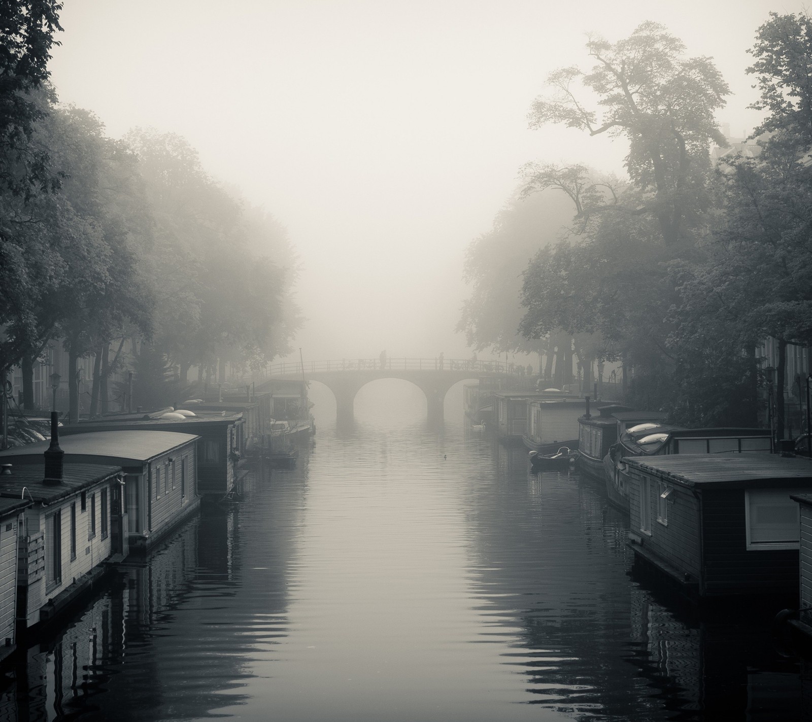 Un bateau qui descend la rivière dans le brouillard (noir, pont, sombre, gris, brume)