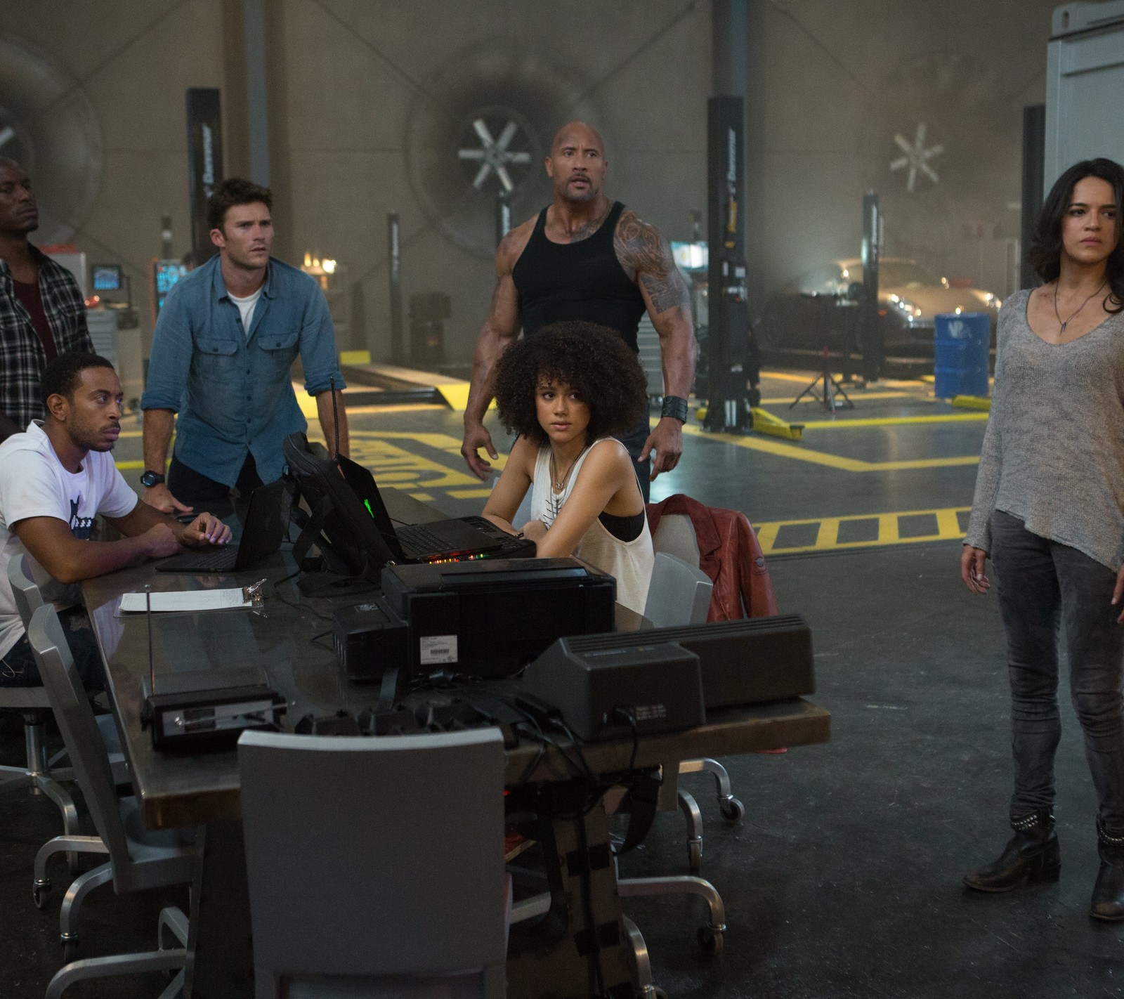 Eine gruppe von menschen steht um einen tisch mit laptops (fast furious, fast and furious, fate of the furious, michelle rodriguez)