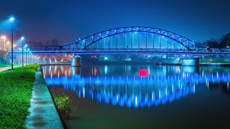 Аркадный мост над рекой ночью с огнями, отражающимися в воде (мост юзефа пилишудского, józef piłsudski bridge, кразув, kraków, польша)