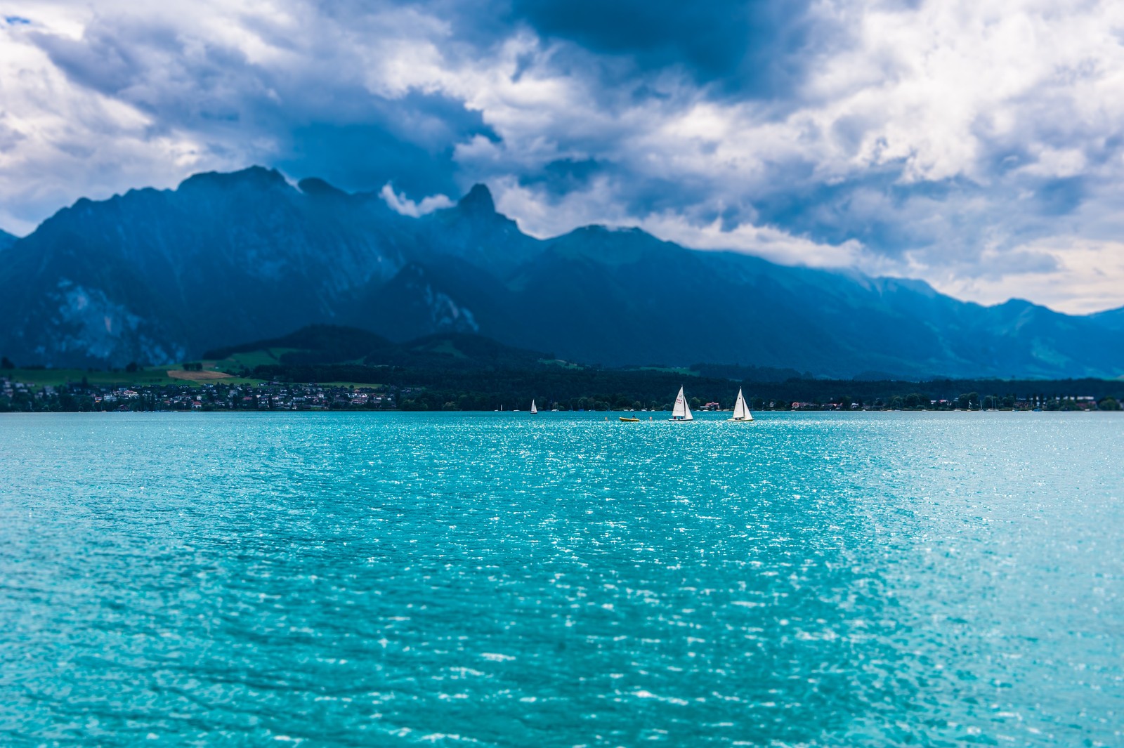 Grupo de veleiros nas águas azuis de um lago com montanhas ao fundo (lake thun, montanhas, dia, sailing boats, natureza)