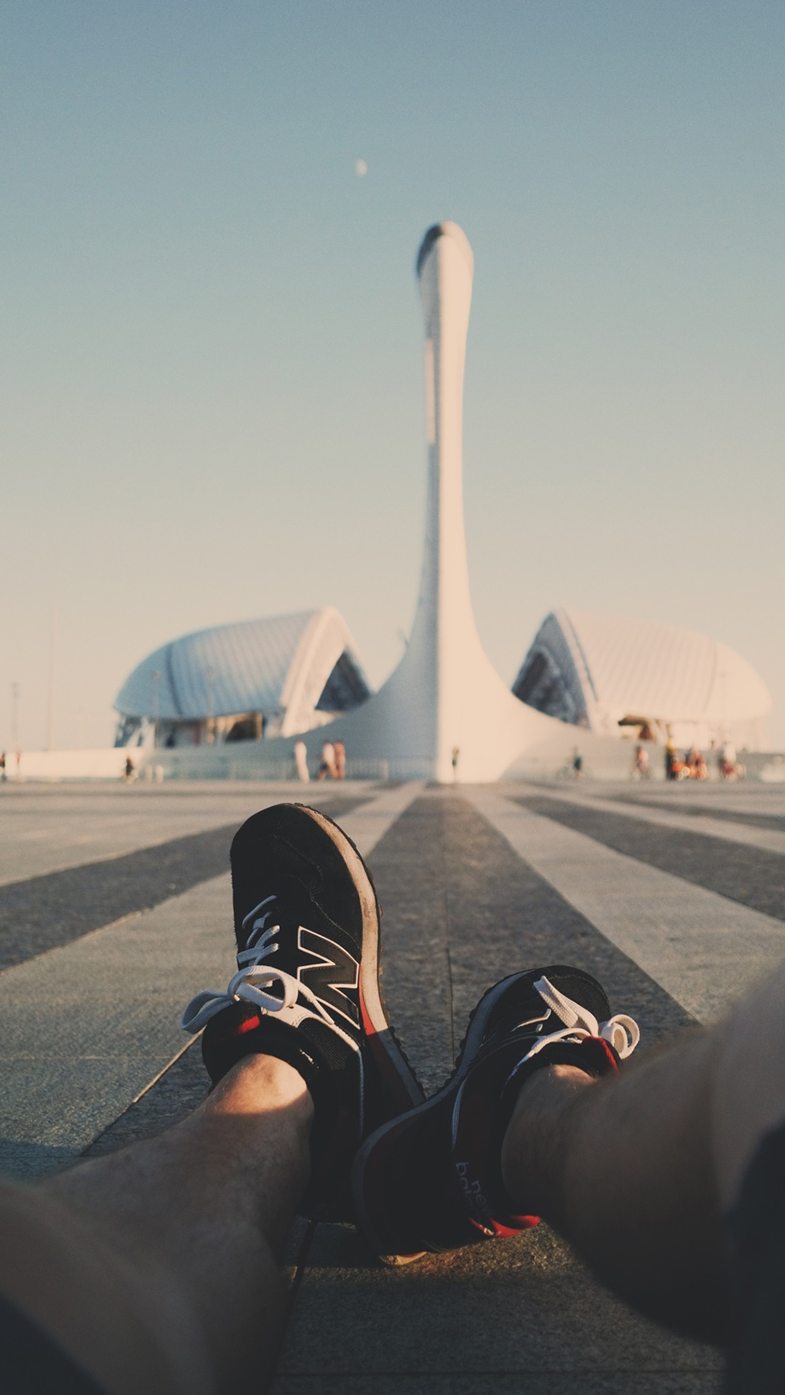 Someone is sitting on the ground with their feet up (shoe, leg, human body, aircraft, flooring)