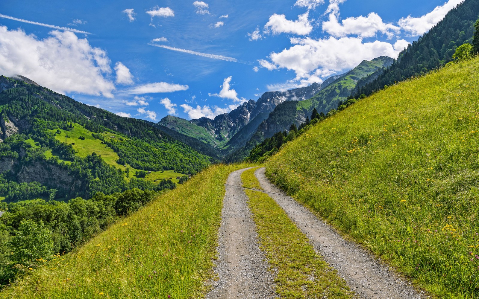 Uma estrada de terra subindo uma colina gramada com montanhas ao fundo (nuvem, montanha, planta, paisagem natural, pessoas na natureza)