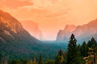 Sonnenaufgang über dem Yosemite-Tal, der majestätische Gebirgszüge und üppige Wildnis zeigt.