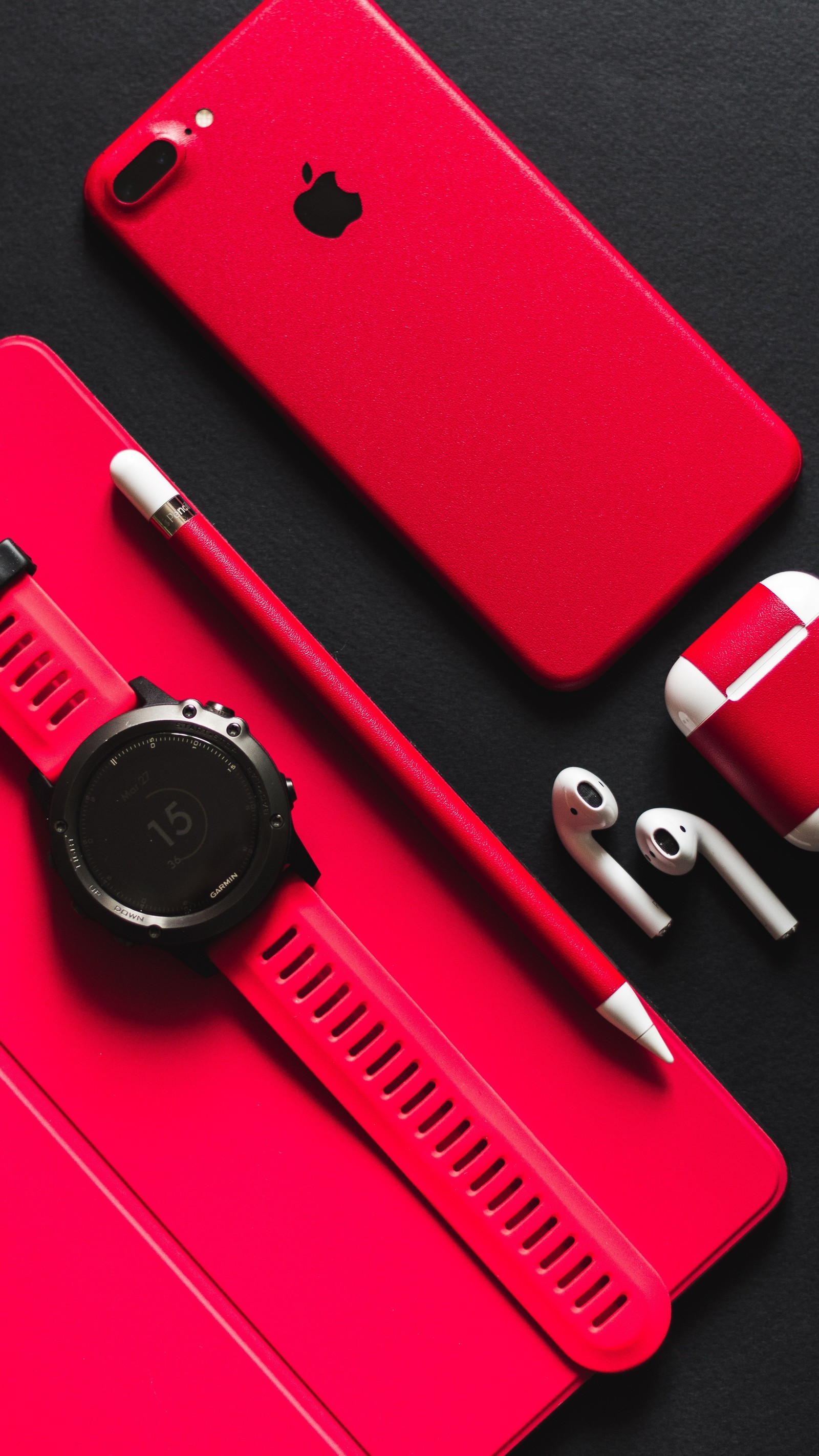 Hay un estuche rojo con un reloj y auriculares sobre él (lujo, manzana, relojes)