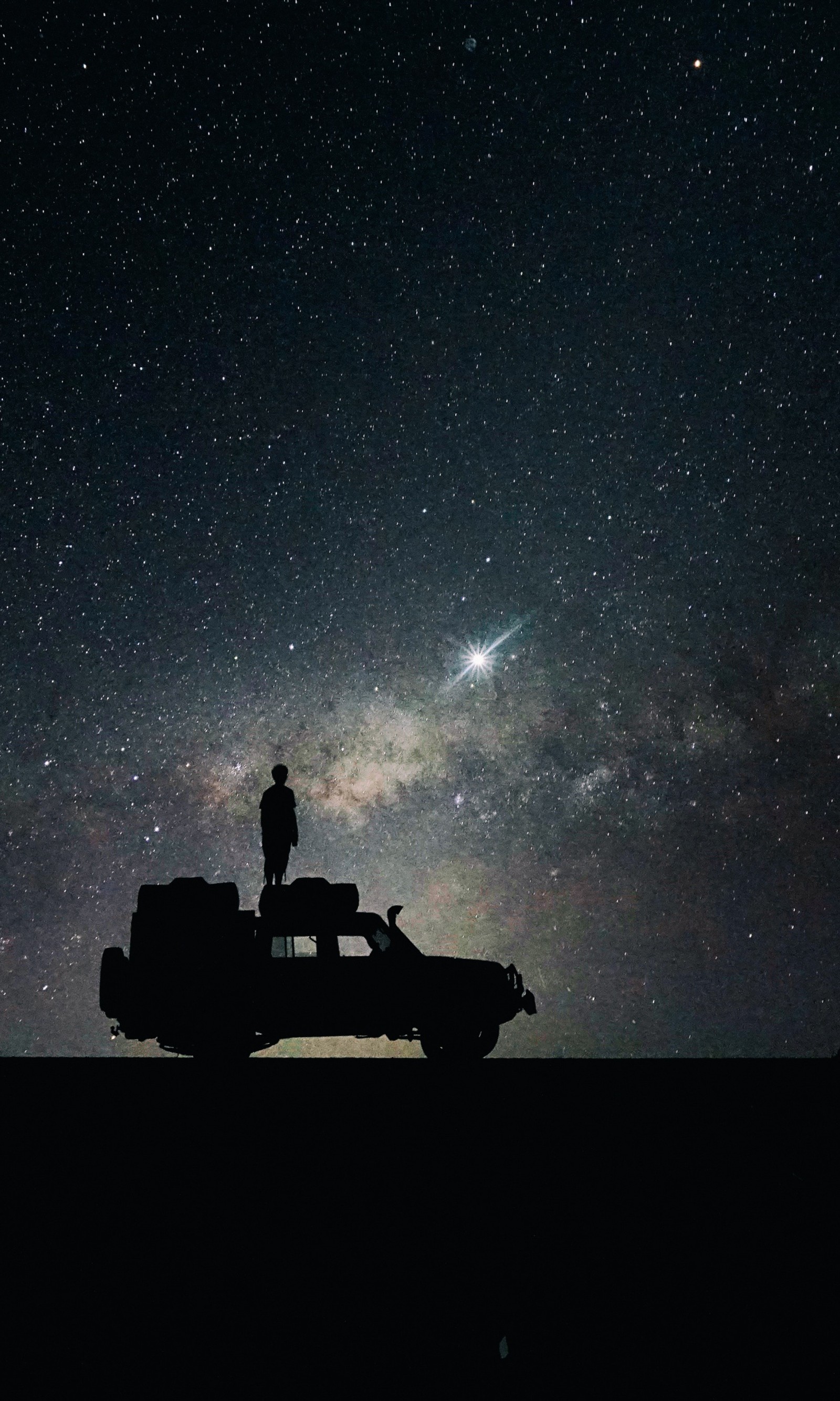 Céu noturno estrelado com a silhueta de um homem em pé sobre um caminhão (galáxia, via láctea, espaço, universo)