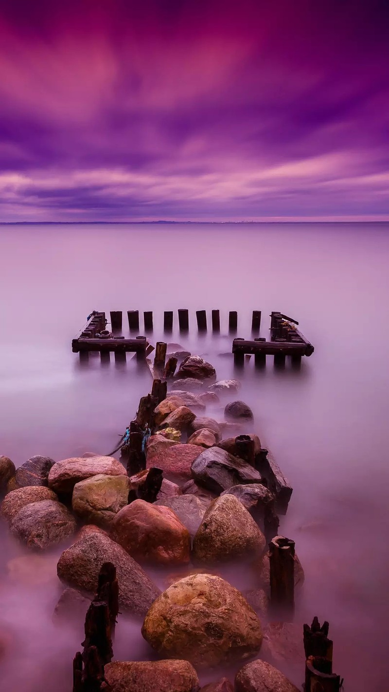 Céu roxo sobre a água e pedras na água (mar, céu, linha do horizonte)