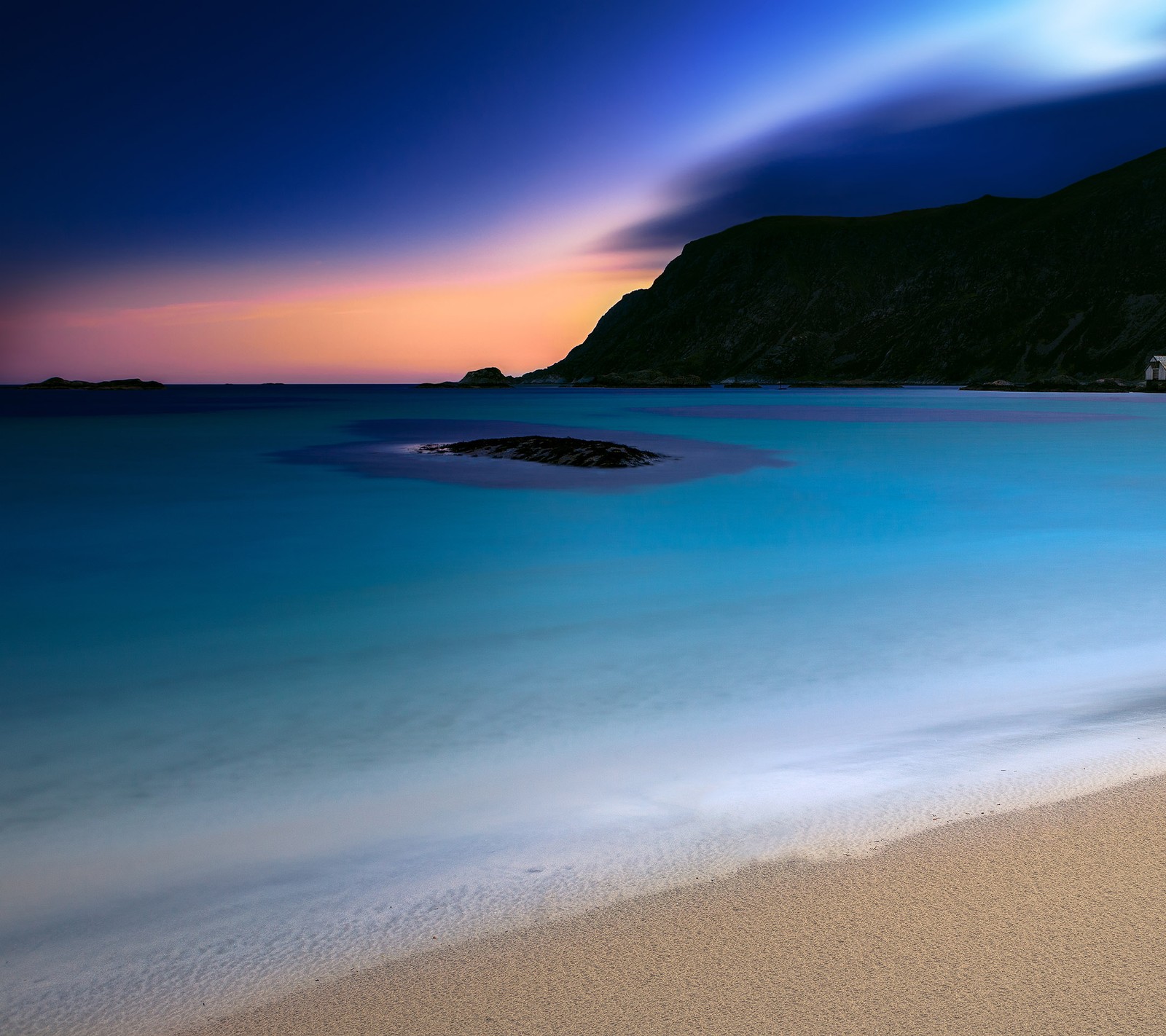 Ein verfälschter blick auf einen strand mit einem berg im hintergrund (beech, blau, wasser)