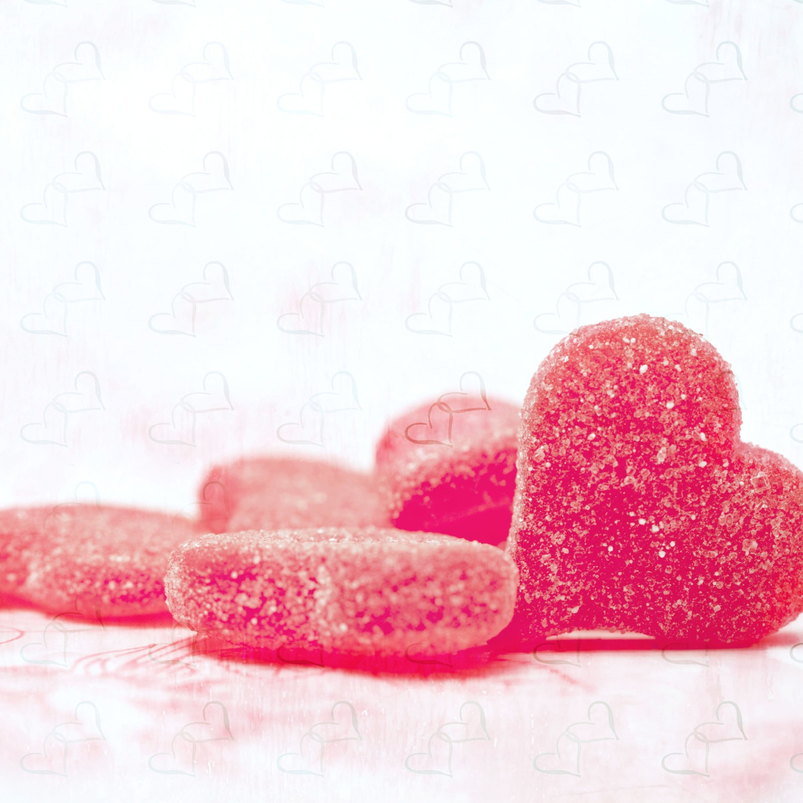 There are two hearts shaped candies on a table with a puzzle background (heart, sugar, food, glitter, cakes)