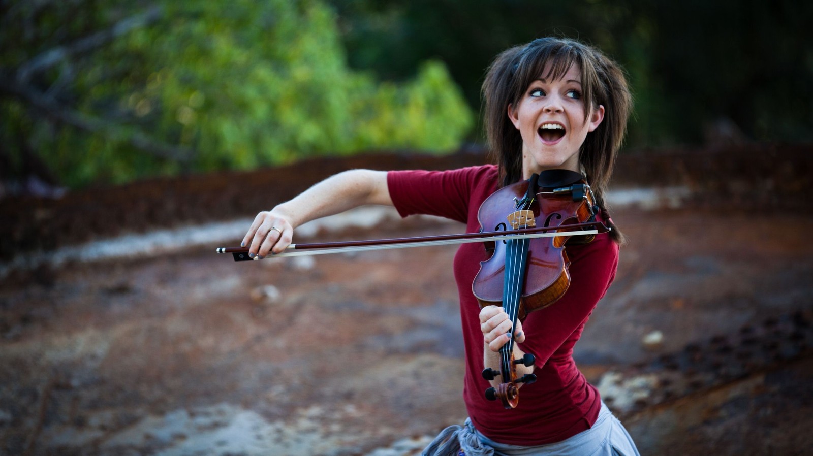 Femme arabe jouant du violon dans une zone boisée avec des arbres en arrière-plan (lindsey stirling, violon, recréation, musique, fille)