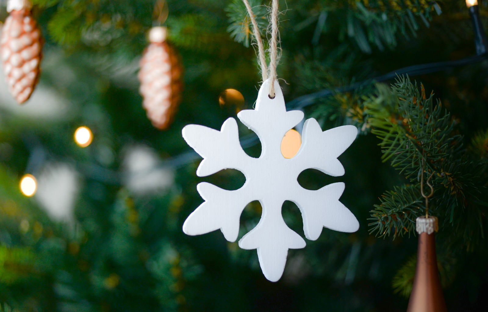 There is a snowflake ornament hanging from a christmas tree (christmas, factory, tree, christmas decoration, snowflake)