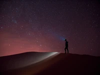 Observation des étoiles dans le désert algérien : Une figure solitaire illuminée par le cosmos