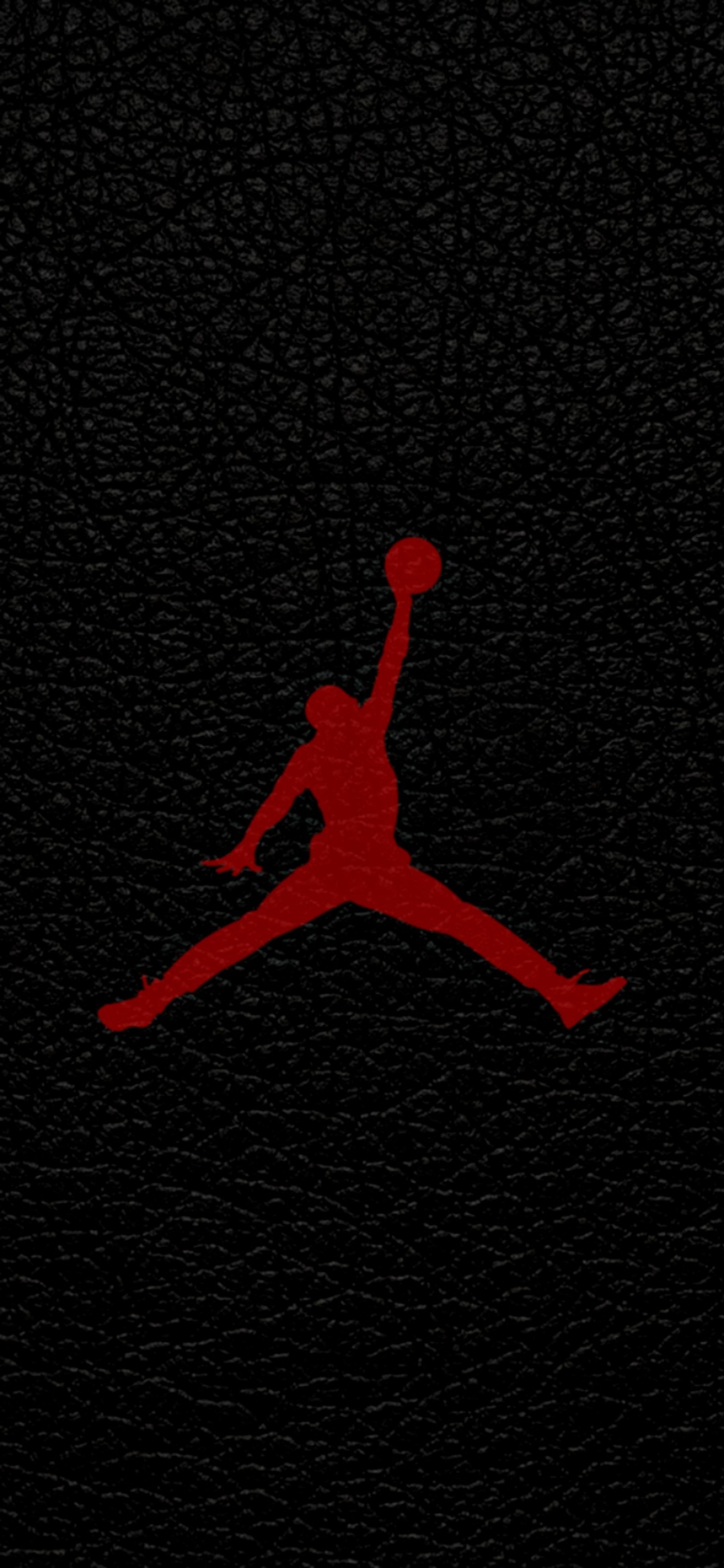 A close up of a red and black air jordan logo on a black leather surface (air, basketball, jordan, logo, sport)