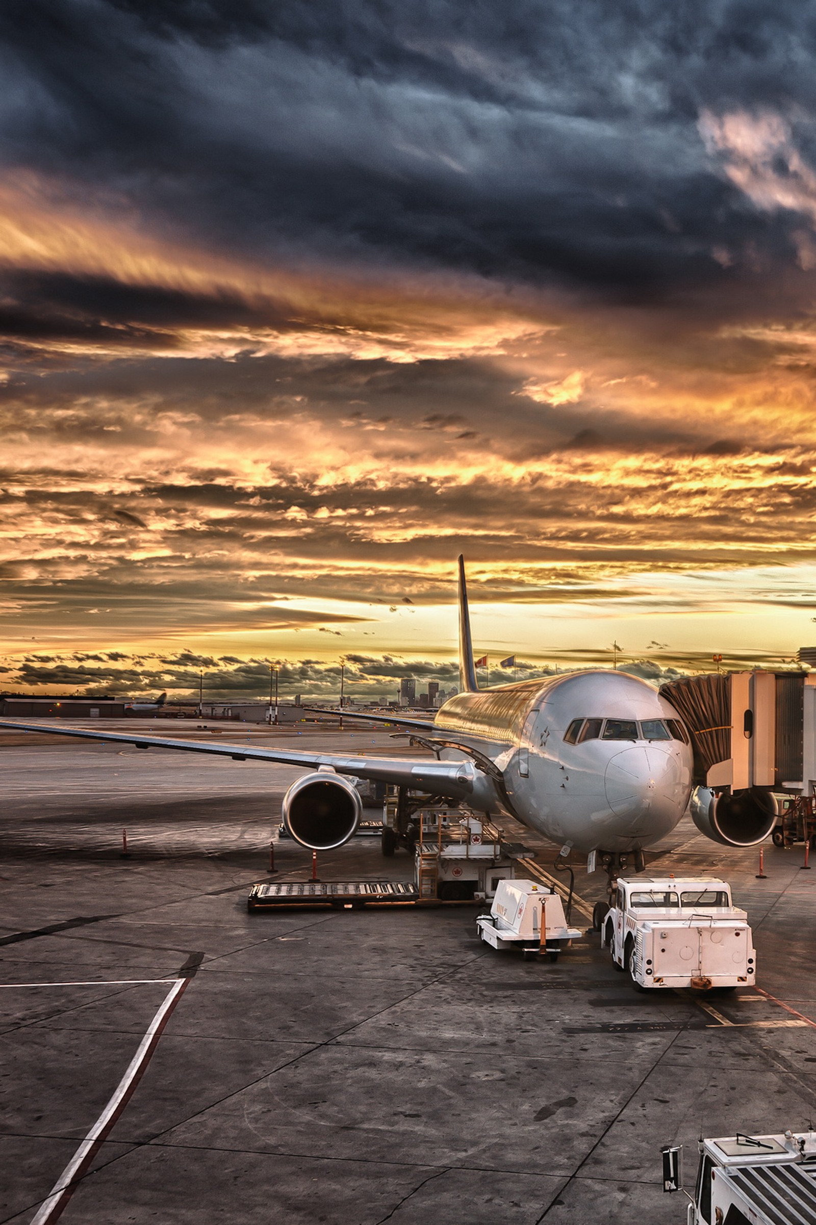 Um avião estacionado em um aeroporto com um caminhão e um avião (aeroporto, nuvens, legal, crepúsculo, ouro)