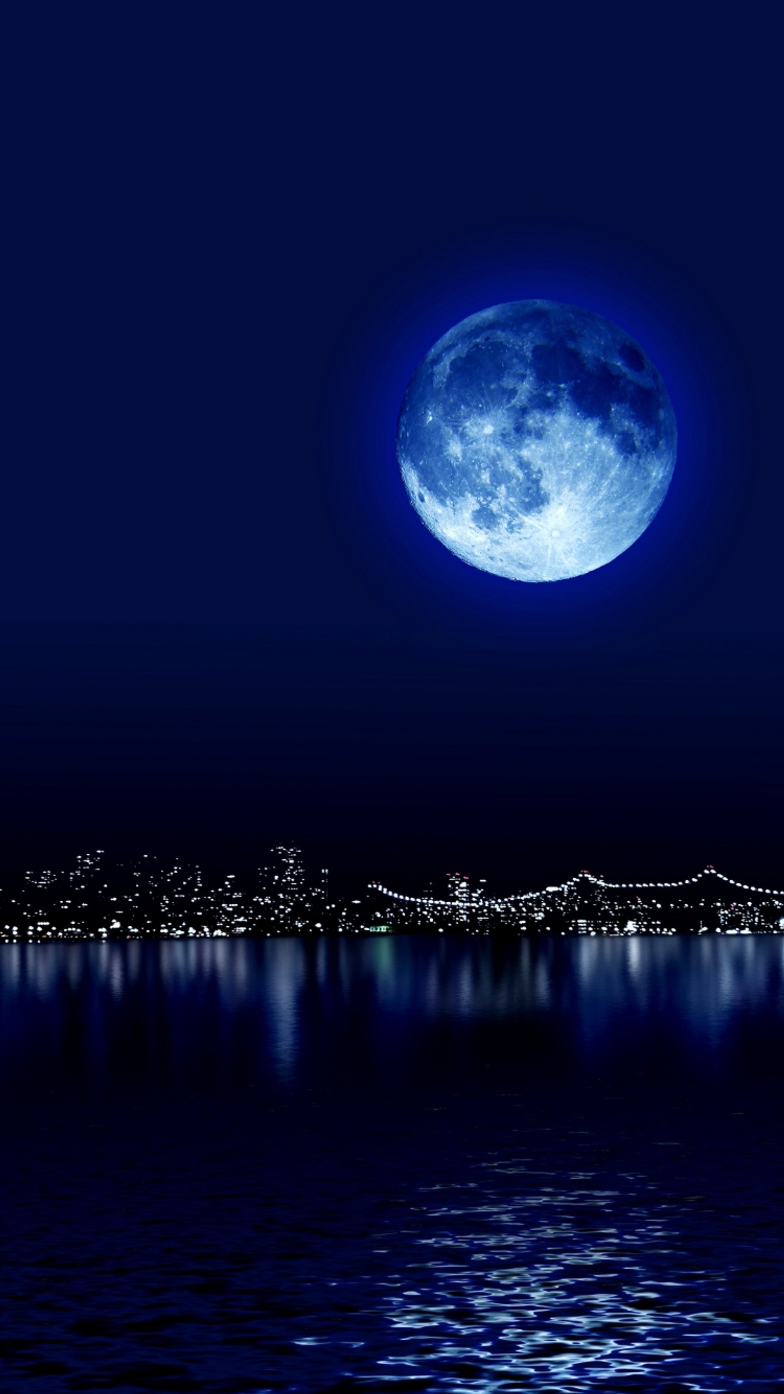 Un primer plano de la luna llena sobre una ciudad de noche (azul, ciudad, luna, noche, reflexión)