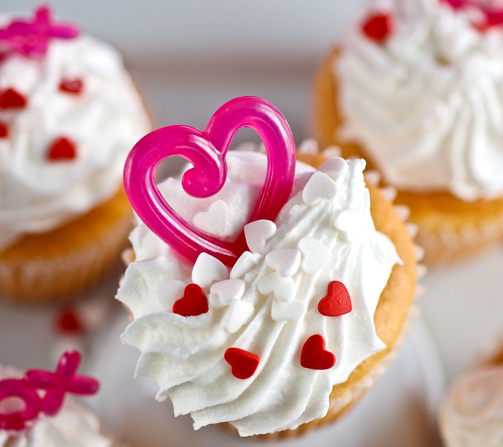 Il y a des cupcakes avec un glaçage blanc et des cœurs roses dessus (gâteau, crème, cupcake, décoration, dessert)