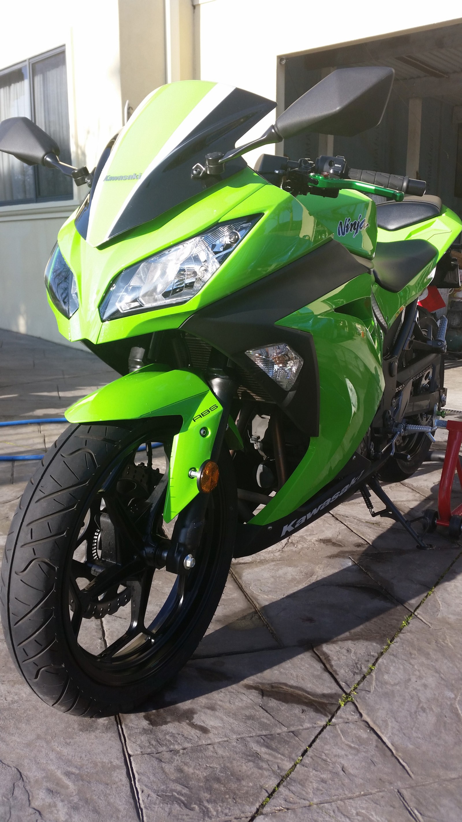 Hay una motocicleta verde estacionada al lado de la calle (300, 300cc, bicicleta, motociclista, verde)