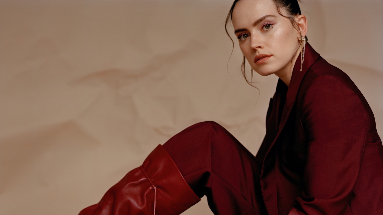 Mujer árabe en un traje rojo y botas rojas sentada en una silla (daisy ridley, inglés, actriz, celebridad, mujeres)