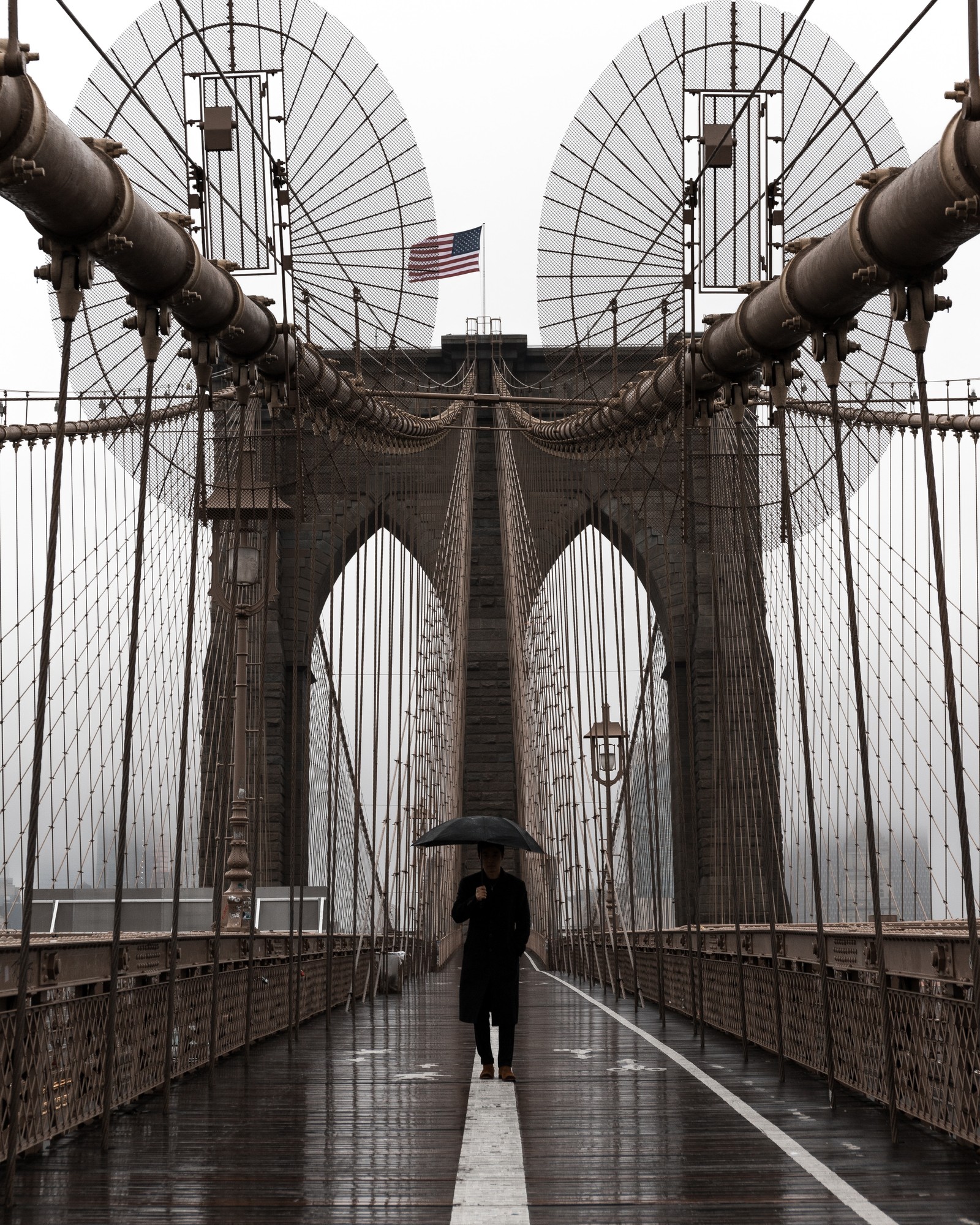 Une girafe arabe marchant sur un pont avec un parapluie sous la pluie (pont de brooklyn, architecture, symétrie, bâtiment, arc)