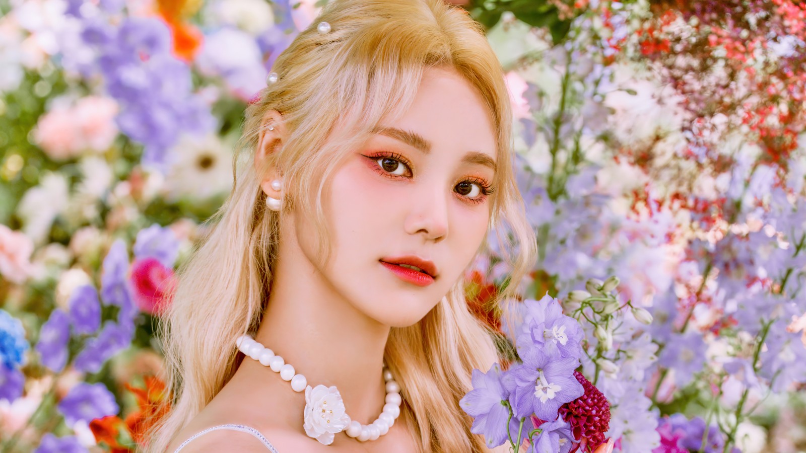 Une femme aux cheveux blonds et en robe blanche se tient dans un champ de fleurs (jinsoul, jinsol, jung jin sol, 정진솔, loona)