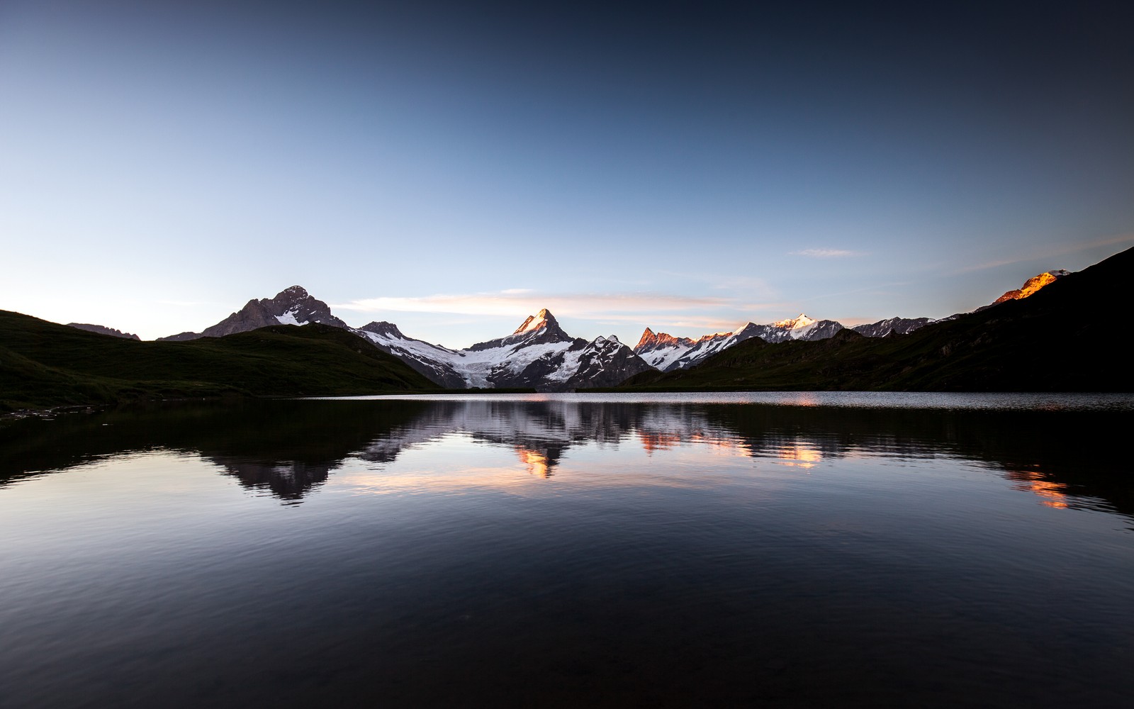 Una impresionante cordillera con un lago y una cordillera en la distancia (amanecer, mañana, bachalpsee, lago, reflejos)