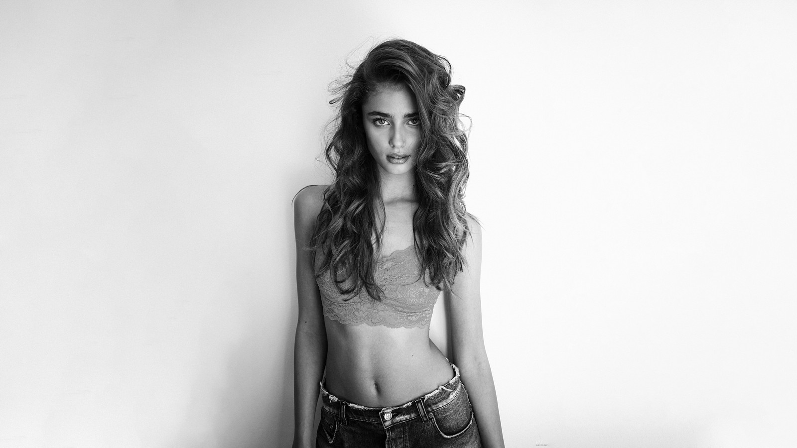 Una mujer árabe en un top de sujetador y jeans apoyada contra una pared (taylor hill, monocromo, 5k, 8k, blanco y negro)