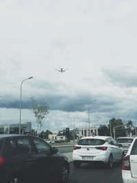 Verkehr unter einem bewölkten Himmel mit einem sich nähernden Flugzeug