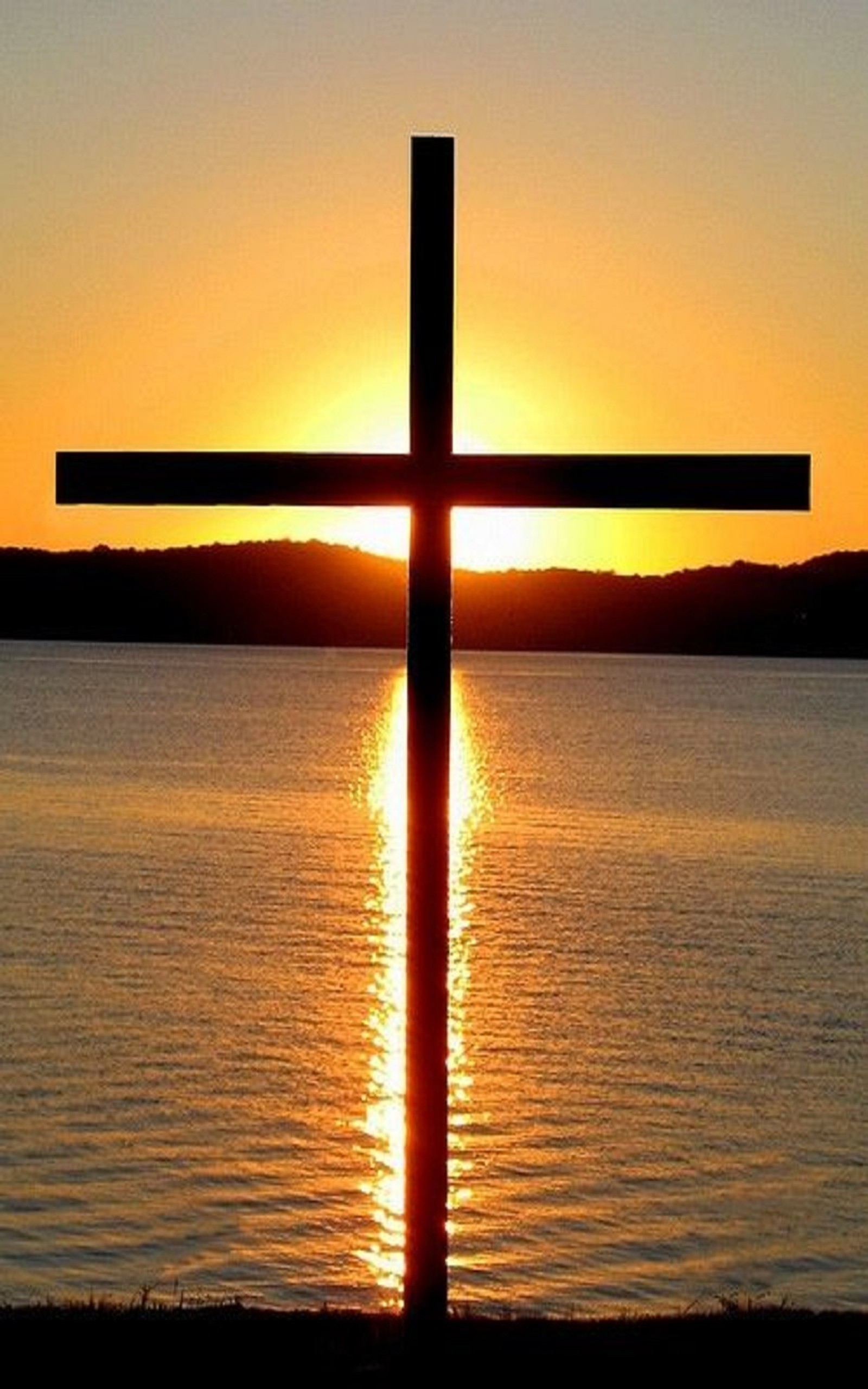 Arafed cross on a beach with the sun setting in the background (cross, sea, sunset)