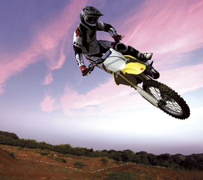 Piloto de motocross freestyle realizando un salto alto contra un cielo dramático