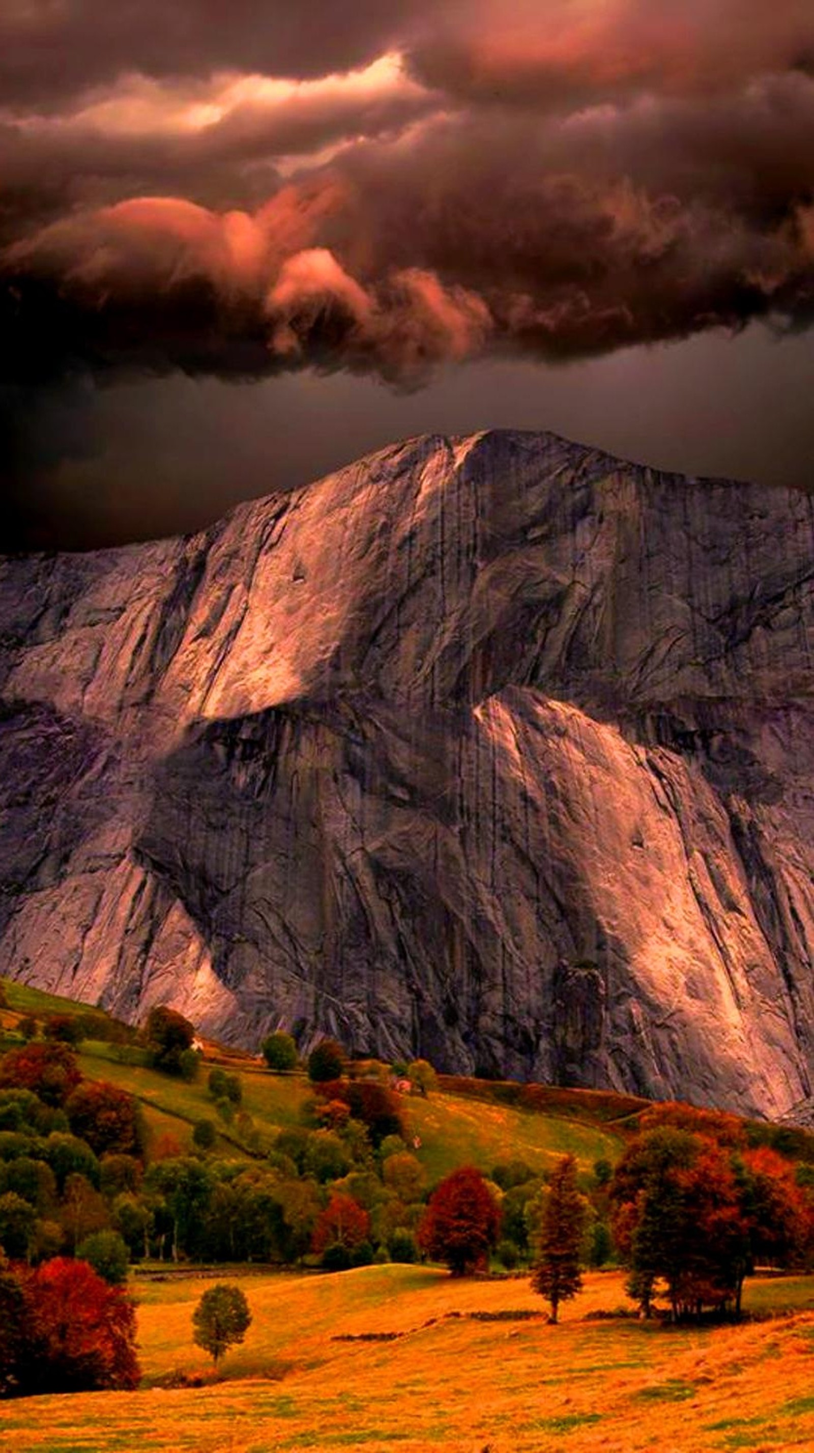 Arafed mountain with a cloudy sky and a few trees (autumn, clouds, rocks, storm)