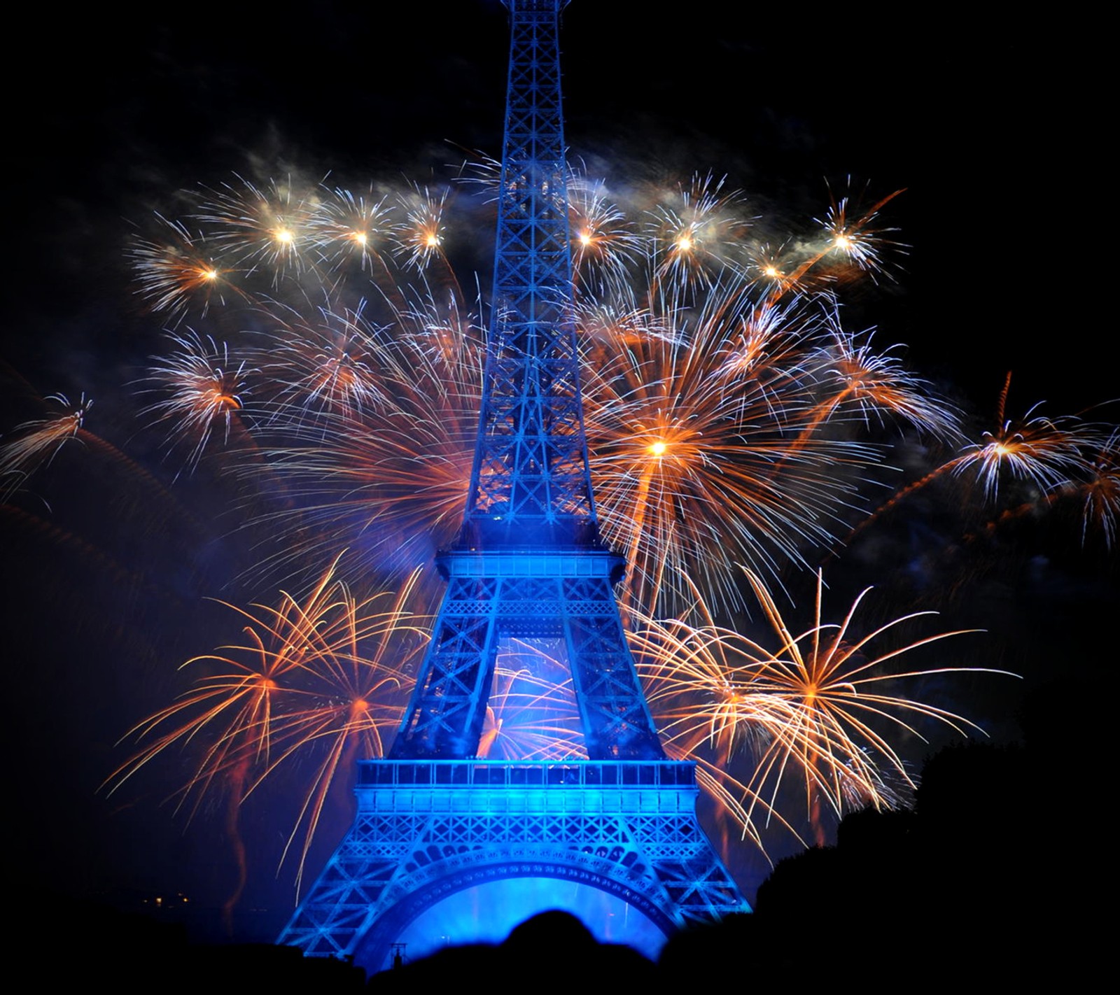 Los fuegos artificiales iluminan el cielo detrás de la torre eiffel. (torre eiffel, luces, noche, parís, paris)